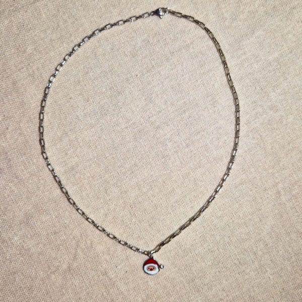 Collier, chaine métal argenté avec pendentif père noël, couleurs rouge et blanc avec zirconium en guise de pompon sur le bonnet du Père Noël.