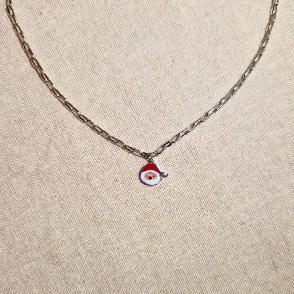 Collier, chaine métal argenté avec pendentif père noël, couleurs rouge et blanc avec zirconium en guise de pompon sur le bonnet du Père Noël.